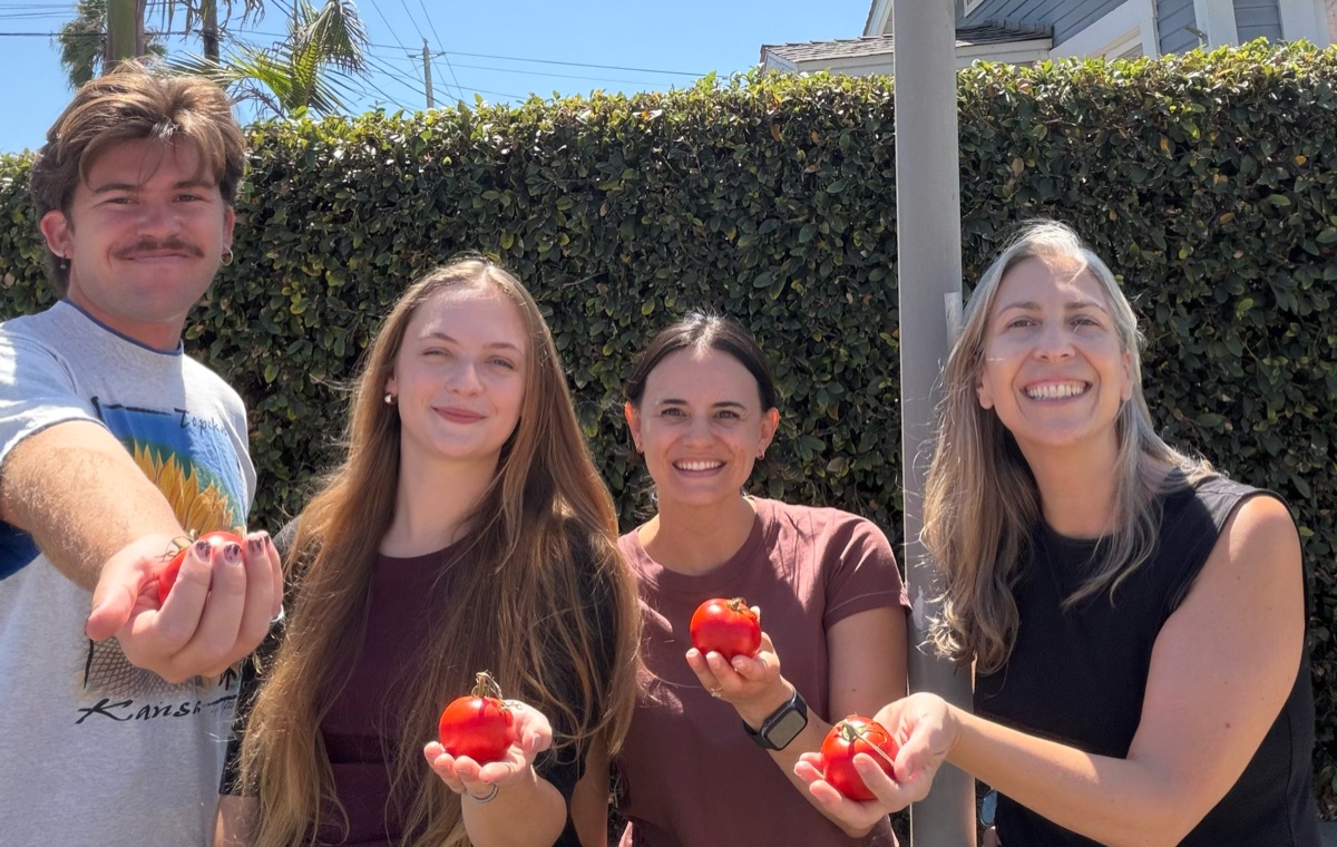 Board members Scott Payne, Molly Ryan, Olivia Sanchez, and Rachel Murray, left to right, each holding a freshly picked tomato.